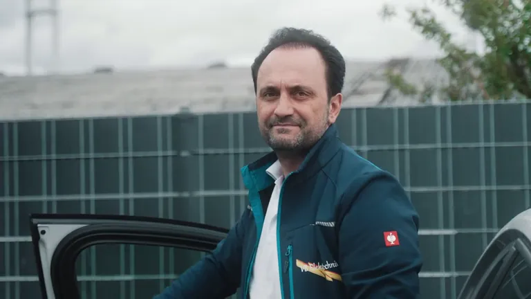 Ein Mitarbeiter von VB Elektrotechnik steht an der offenen Tür des Firmenwagens